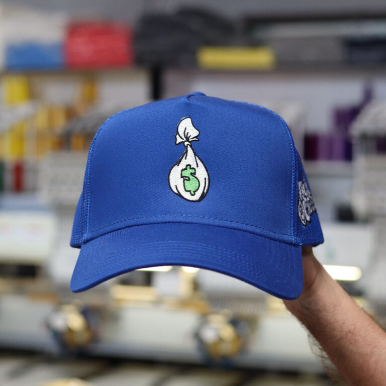Blue baseball cap with a money bag emblem displayed in a store.