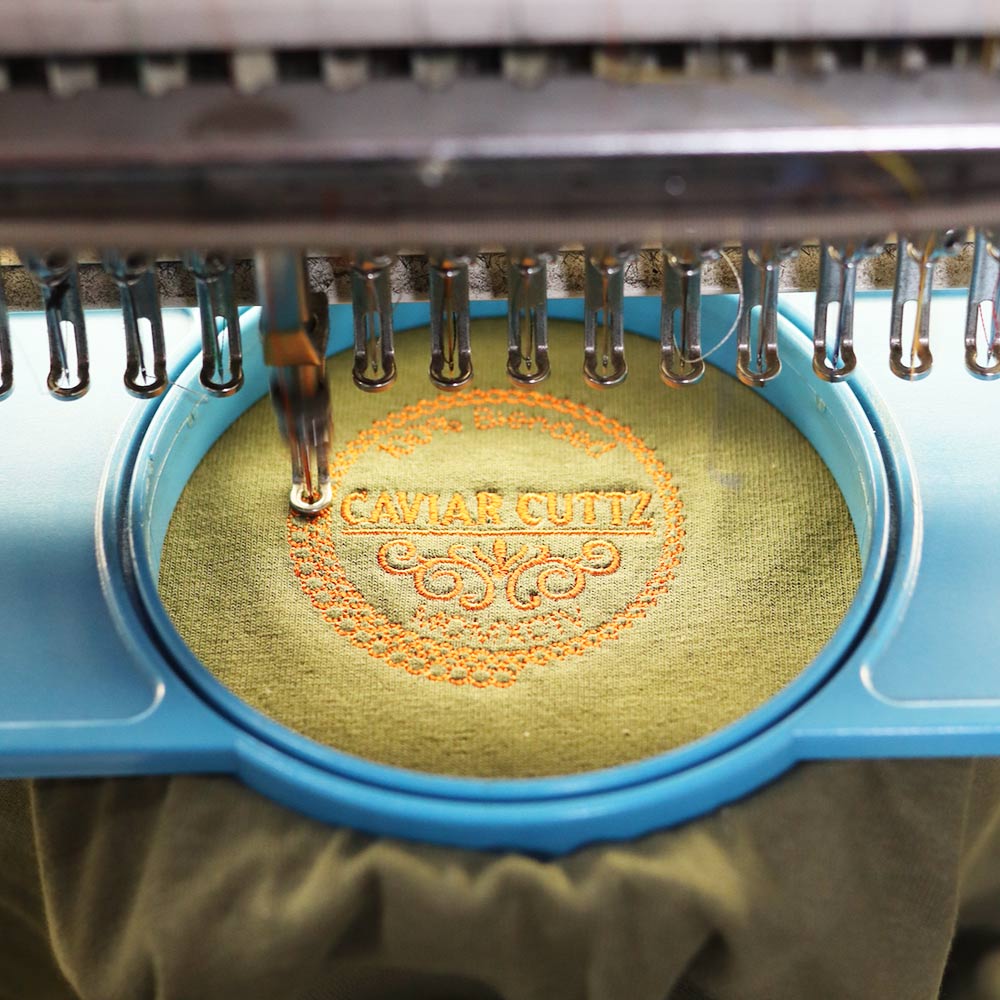 Embroidery machine stitching a logo onto fabric.