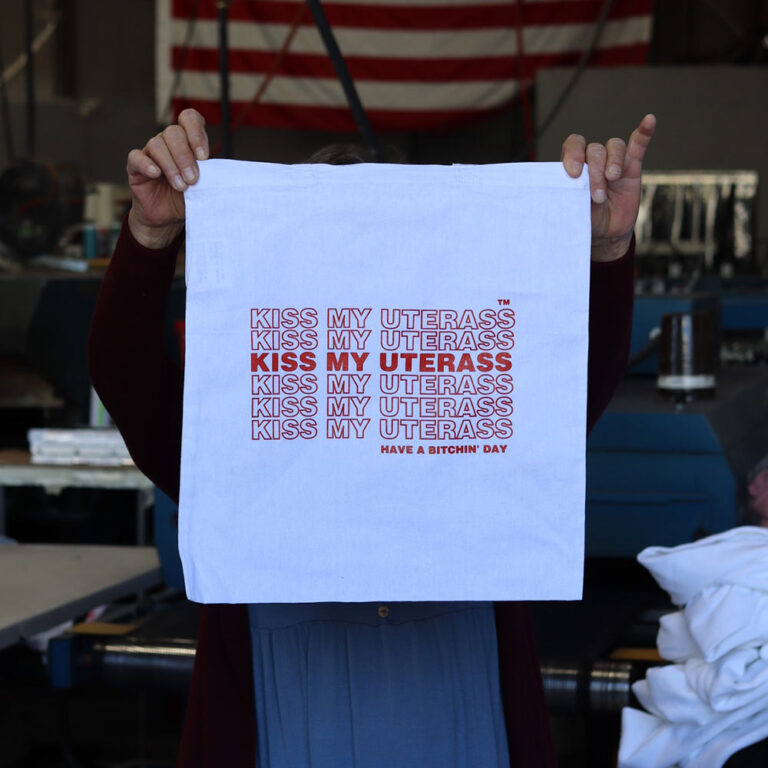 This is a photo of custom screen printed tote bags in white with red ink