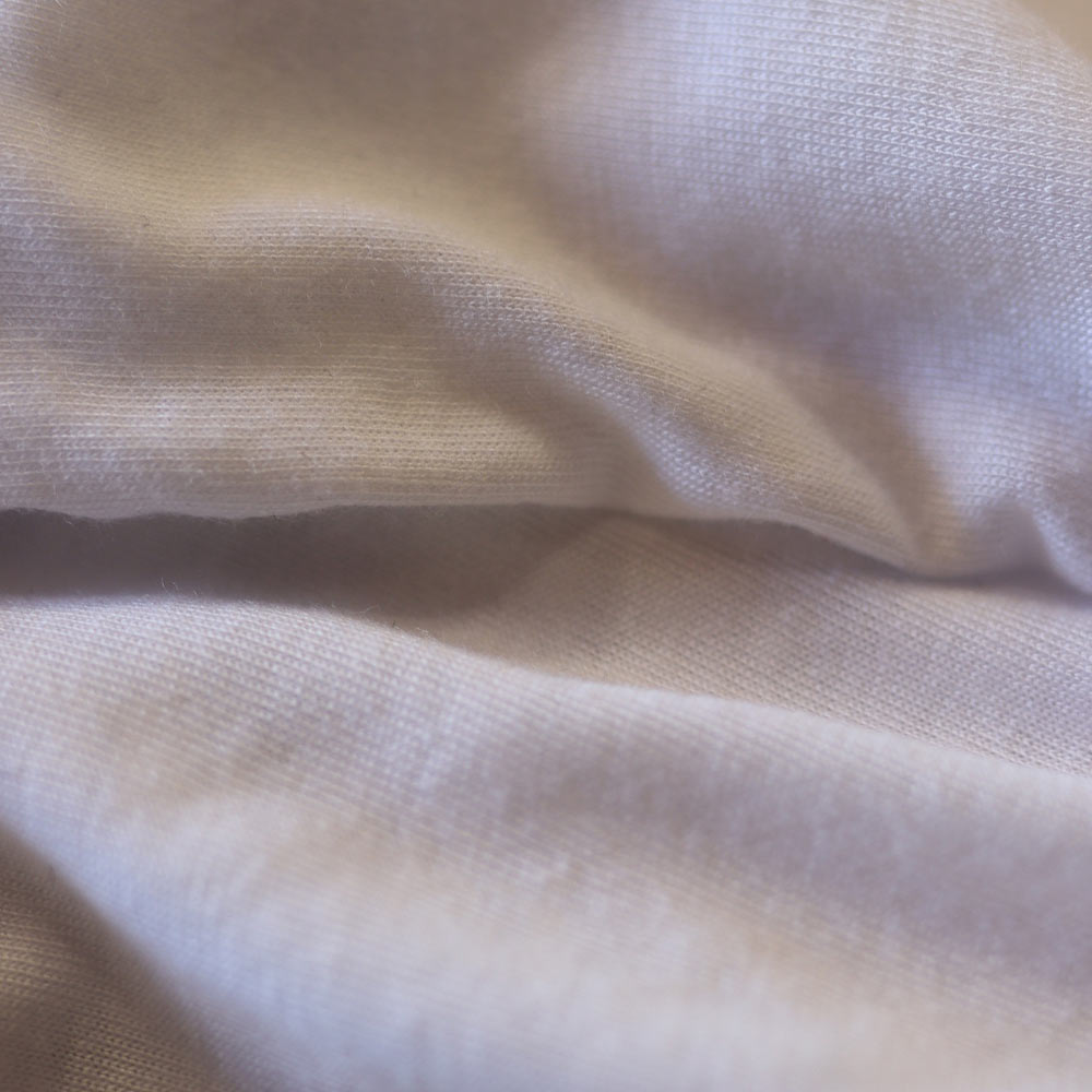 Macro shot of the lightweight fabric of the Bella + Canvas 8882 Women’s Flowy Crop Tee in white. The high-quality material ensures comfort and breathability, while Garment Decor’s screen print blends seamlessly with the fabric for a soft touch.