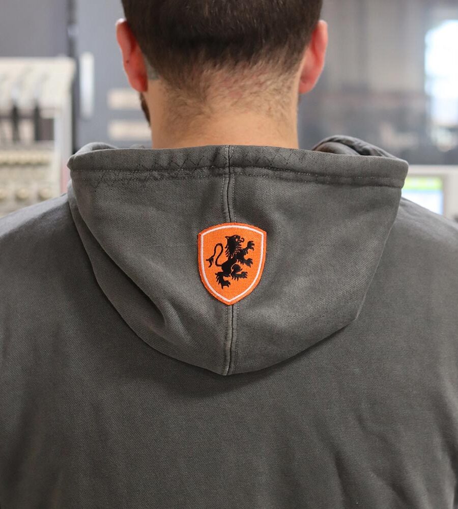 The back view of the hoodie highlights a striking custom-embroidered patch featuring a bold orange shield with a black lion emblem. Positioned neatly on the hood, this element adds a touch of sophistication and uniqueness to the Independent Trading Co. PRM4500 Hoodie. Garment Decor’s embroidery craftsmanship ensures sharp detail and lasting quality, making this piece stand out in any wardrobe.
