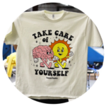 A t-shirt for brands with a graphic design featuring a brain and a smiling sun, accompanied by the text "take care of yourself.