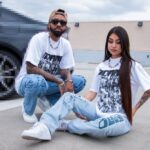 Two individuals modeling Custom Printed Heavyweight Cotton T-Shirts and denim while sitting on a rooftop.