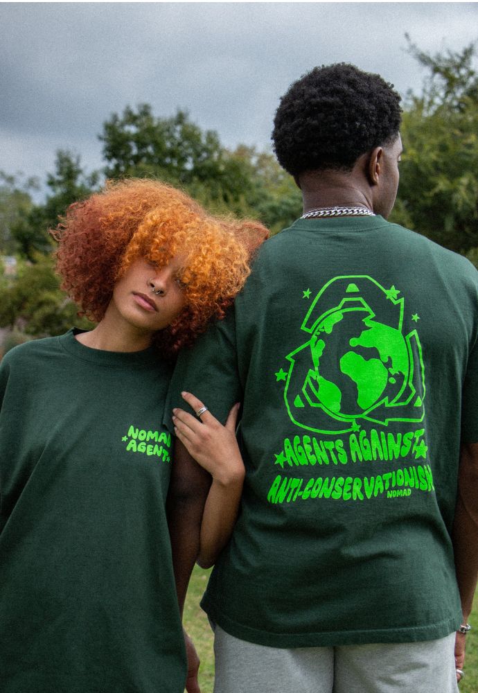 Two individuals showcasing the back designs of their green t-shirts with environmental messages.