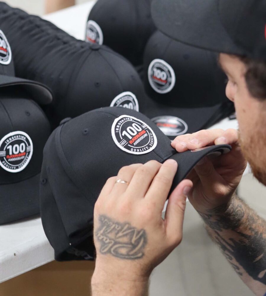 A person applying a sticker to a black baseball cap.