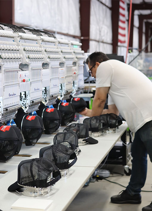 A technician calibrates embroidery machines in a production facility.