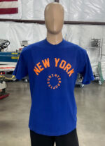 A mannequin is dressed in one of the 100 Garment-Dyed Heavyweight Shirts - Text-Based Artwork with Vector Designs - Maximum of 2 Ink Colors - Soft Hand Screen Printing, standing in an industrial workspace. Machinery and equipment are visible in the background.