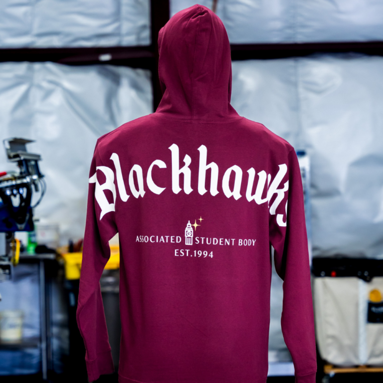 A mannequin wearing the back view of Maroon Independent Trading Co. SS4500 Midweight Hooded Sweatshirt with jumbo screen print design for La Quinta Blackhawks by Garment Decor. - Garment Decor A mannequin wearing the back view of Maroon Independent Trading Co. SS4500 Midweight Hooded Sweatshirt with jumbo screen print design for La Quinta Blackhawks by Garment Decor.