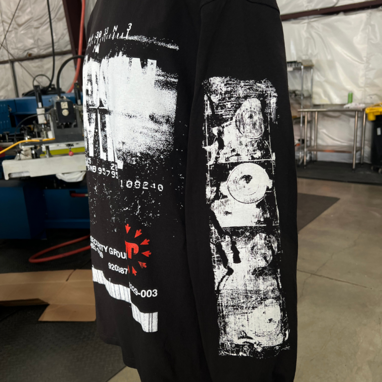 American Apparel 1304 Heavyweight Cotton Long Sleeve Tee Custom Jumbo Screen Print Black Side View - Garment Decor A photo of a black American Apparel 1304 Heavyweight Cotton Long Sleeve Tee featuring a bold, distressed jumbo screen print design on the front view and sleeve view with text reading 'Lay Down My Life.' Ideal for brands looking for unique, high-impact garment designs. Printed by Garment Decor, specializing in custom jumbo screen printing with advanced digital squeegee technology for vibrant, long-lasting results.