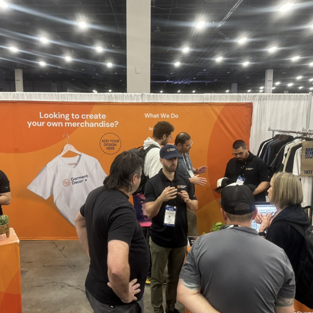 This is a photo of Adryan Lado at the PPAI 2024 Las Vegas Trade Show speaking to customers in the Garment Decor trade show booth.