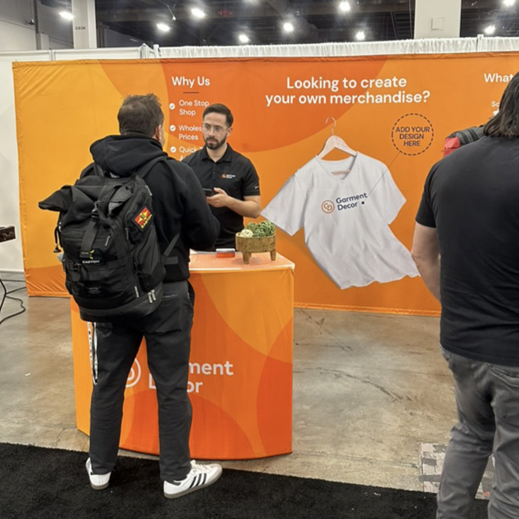 This is a photo of Devyn Lado at the PPAI 2024 Las Vegas Trade Show speaking to customers in the Garment Decor trade show booth.