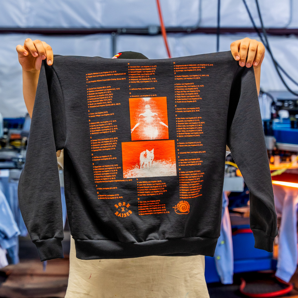 The man holding and showing the back view of pigment black Independent Trading IND420XD Mainstreet 420gm Heavyweight Pullover Hoodie, enhanced with a bold, custom jumbo screen print of Born Online design. Perfect for streetwear brands looking for premium-quality customization - Garment Decor The man holding and showing the back view of pigment black Independent Trading IND420XD Mainstreet 420gm Heavyweight Pullover Hoodie, enhanced with a bold, custom jumbo screen print of Born Online design. Perfect for streetwear brands looking for premium-quality customization