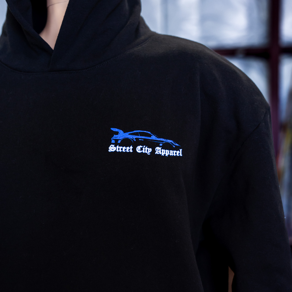 The zoomed in front view of Black Independent Trading Co. IND420XD MAINSTREET 420GM HEAVYWEIGHT PULLOVER HOOD with custom street city artwork screen printed by Garment Decor