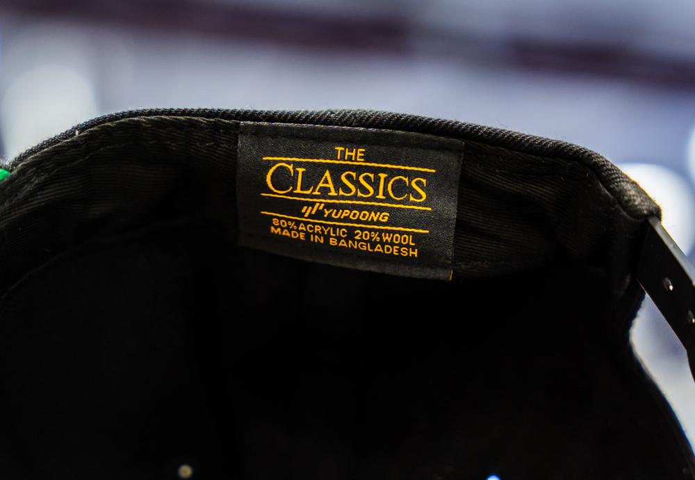 A zoomed in view of the inside label on a Yupoong 6089 Premium Flat Bill Snapback Cap in black, reflecting the craftsmanship and authenticity of this streetwear essential.